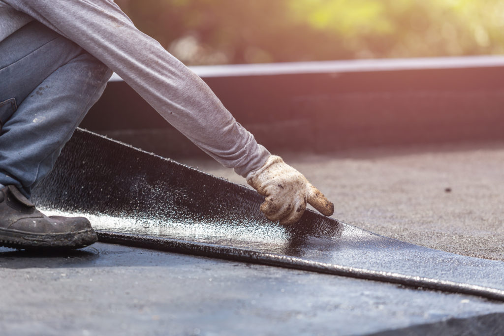 man working to prevent common flat roof problems
