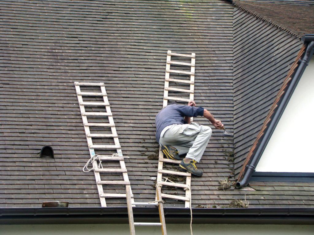 man scraping lichens off a roof