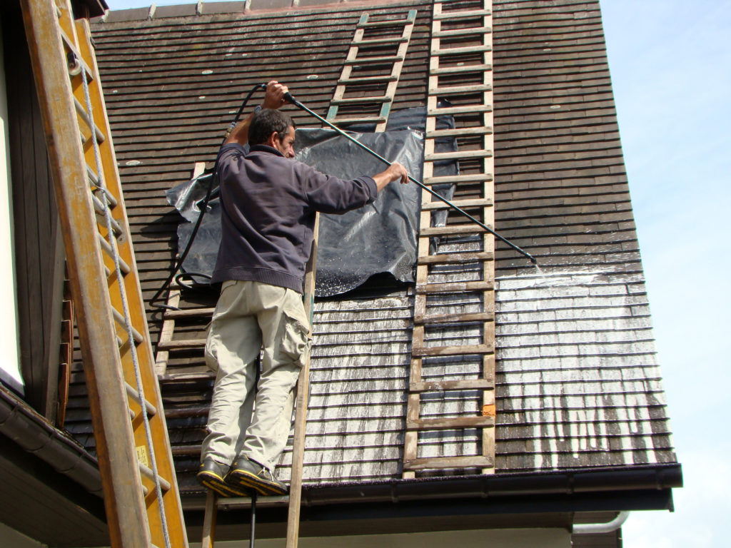 Man spraying roof to remove lichens
