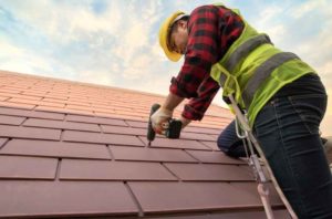 Roofer wearing harness is repairing an asphalt shingle roof