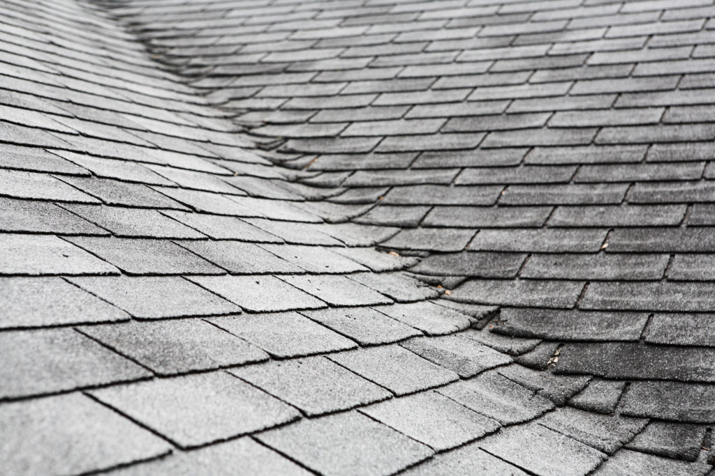 an old roof shows signs of damage with discolored shingles