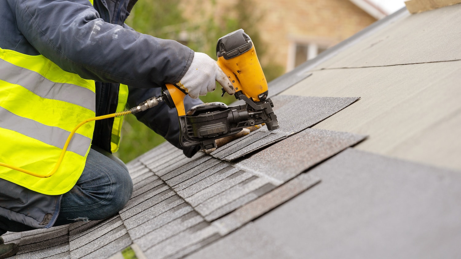 roof repair worker completing shingle replacement with roofing nail gun